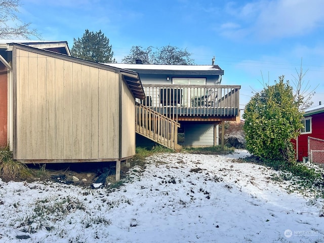 snow covered back of property featuring a deck