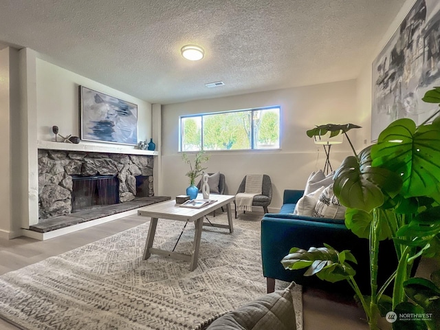 living room with a stone fireplace, hardwood / wood-style floors, and a textured ceiling