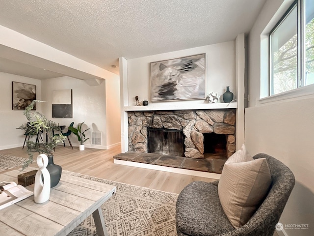 living room with a fireplace, light hardwood / wood-style flooring, and a textured ceiling