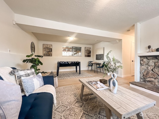 living room with a fireplace, a textured ceiling, and light hardwood / wood-style flooring