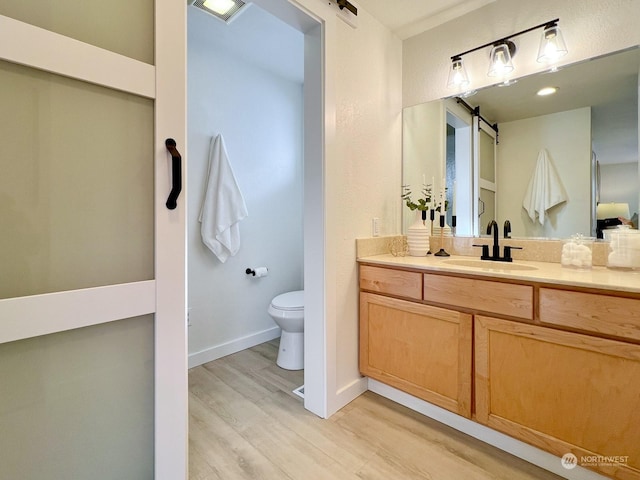 bathroom featuring vanity, hardwood / wood-style flooring, and toilet