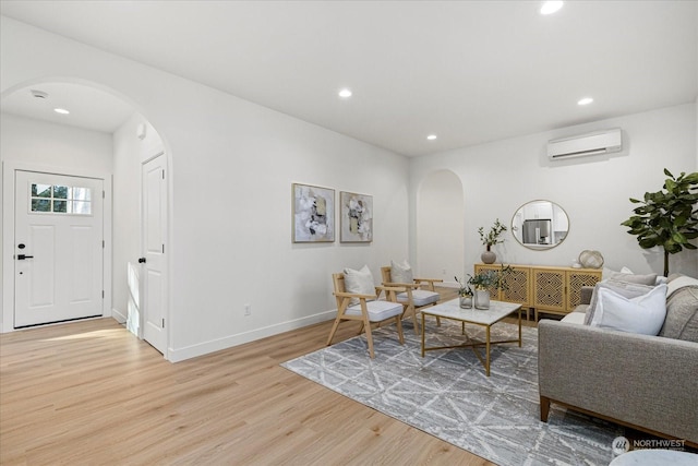 living room with a wall mounted air conditioner and light wood-type flooring