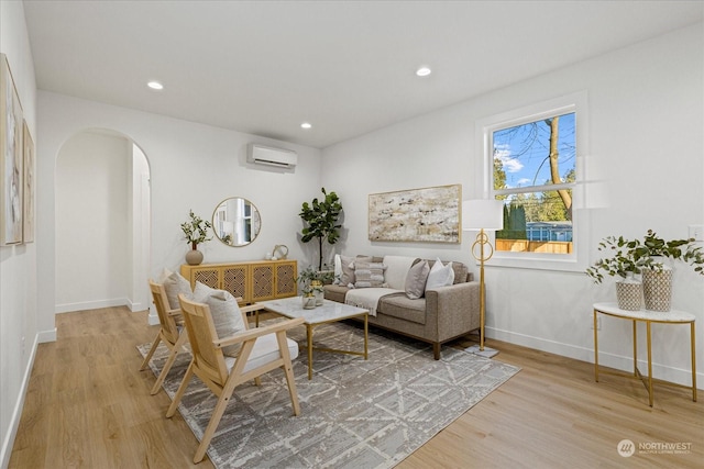 living room with a wall mounted air conditioner and light hardwood / wood-style flooring