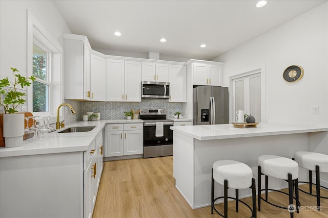 kitchen featuring appliances with stainless steel finishes, white cabinetry, sink, backsplash, and kitchen peninsula