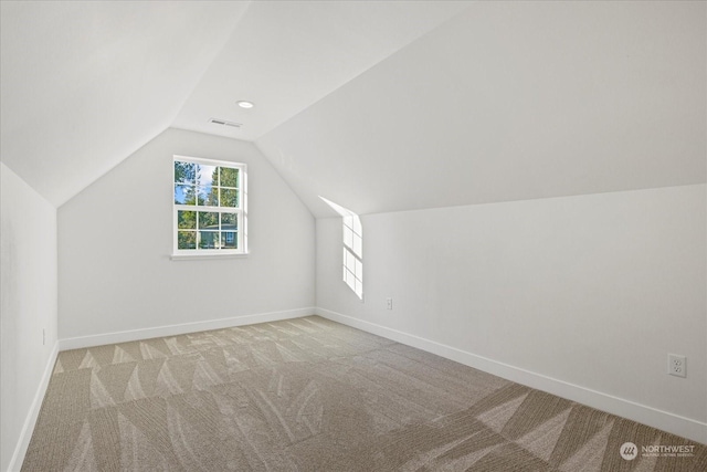 additional living space featuring vaulted ceiling and light colored carpet