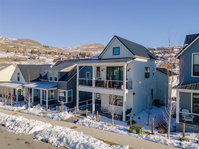 snow covered property with a mountain view and a balcony