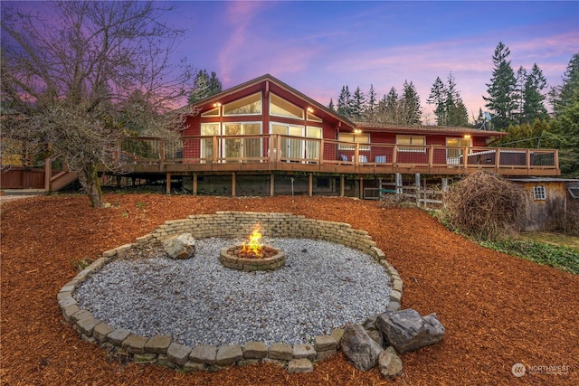 back house at dusk featuring a wooden deck and an outdoor fire pit