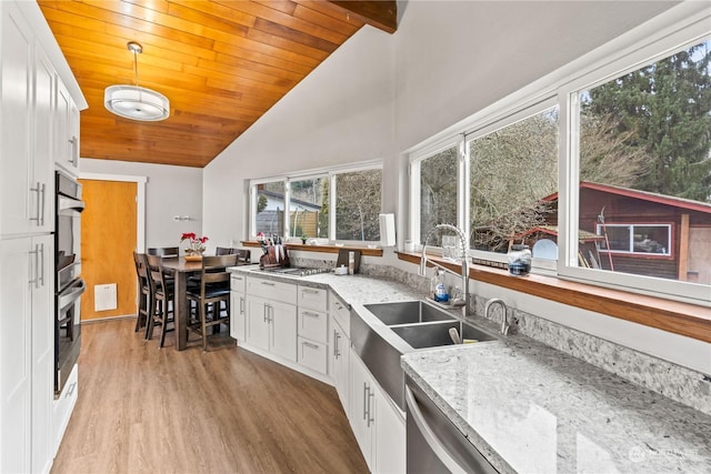 kitchen with pendant lighting, sink, light stone counters, and white cabinets