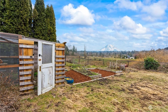 view of outdoor structure with a mountain view, a rural view, and a lawn