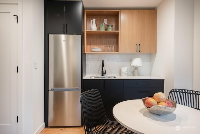 kitchen featuring light hardwood / wood-style floors, sink, stainless steel refrigerator, and decorative backsplash