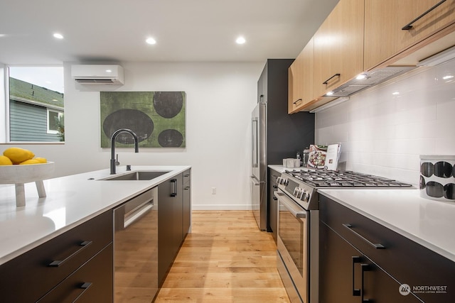 kitchen with appliances with stainless steel finishes, a wall mounted air conditioner, sink, decorative backsplash, and light hardwood / wood-style flooring