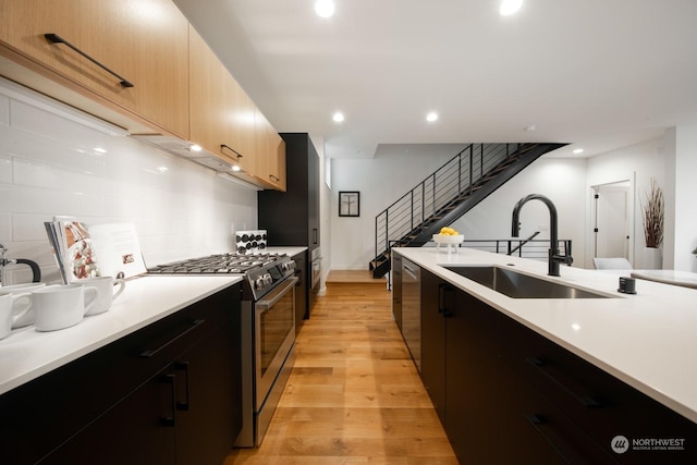 kitchen featuring light brown cabinetry, sink, tasteful backsplash, light wood-type flooring, and stainless steel appliances