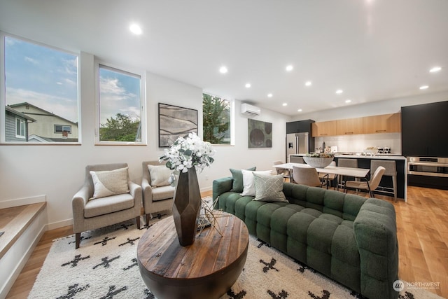 living room with sink, light hardwood / wood-style floors, and a wall unit AC