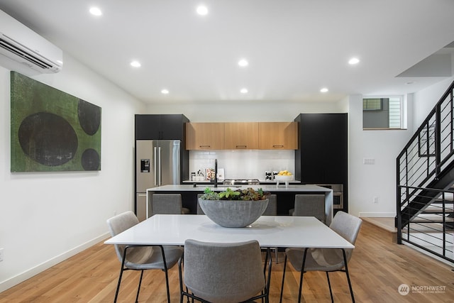 kitchen with a kitchen breakfast bar, an island with sink, high end refrigerator, and a wall unit AC