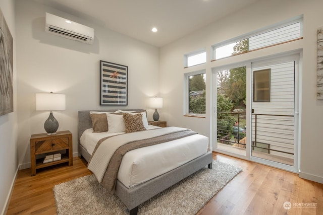 bedroom featuring a wall mounted air conditioner, access to outside, and light hardwood / wood-style floors