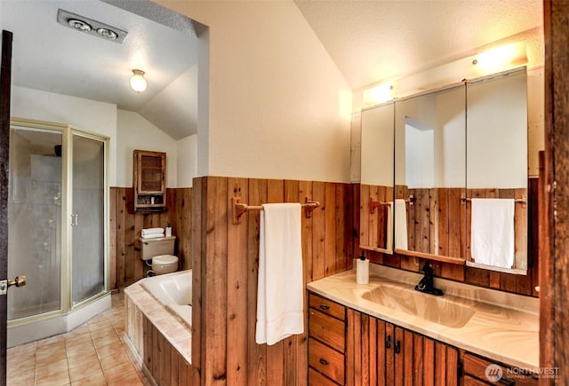 bathroom featuring wooden walls, toilet, vaulted ceiling, wainscoting, and a stall shower