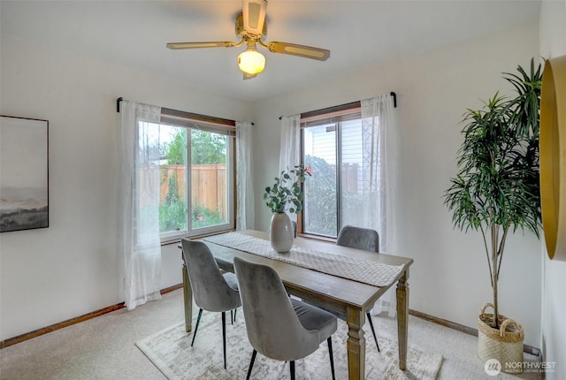 dining room featuring light carpet, baseboards, and ceiling fan