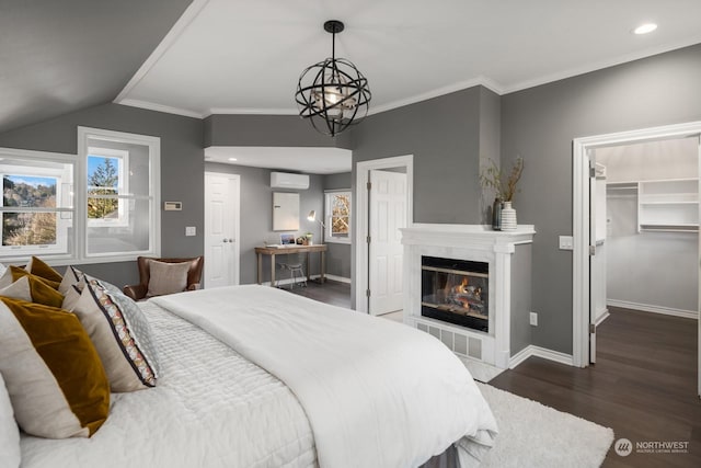 bedroom featuring crown molding, a wall mounted AC, a fireplace, dark hardwood / wood-style flooring, and a walk in closet