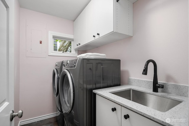 washroom featuring sink, washing machine and dryer, cabinets, and electric panel