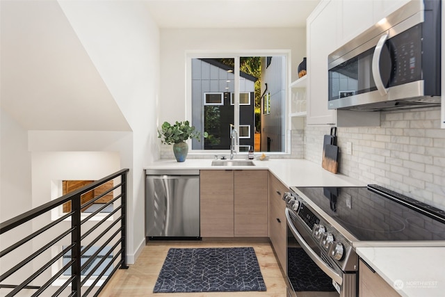 kitchen with sink, light hardwood / wood-style flooring, stainless steel appliances, white cabinets, and decorative backsplash