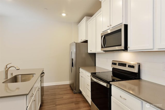 kitchen featuring sink, appliances with stainless steel finishes, white cabinetry, dark hardwood / wood-style flooring, and decorative backsplash