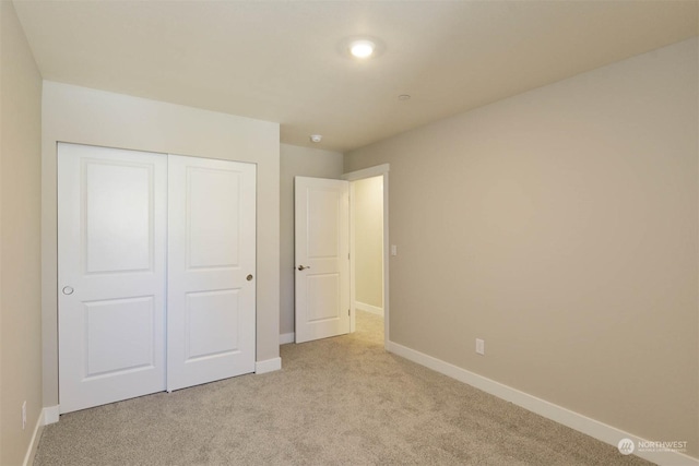 unfurnished bedroom featuring light carpet and a closet