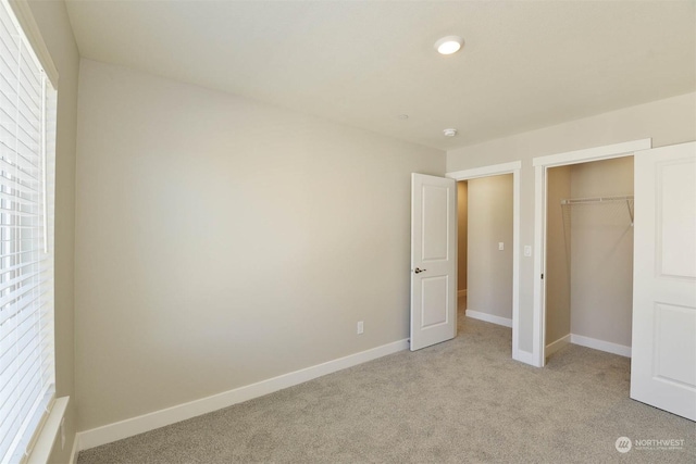 unfurnished bedroom featuring light colored carpet and a closet