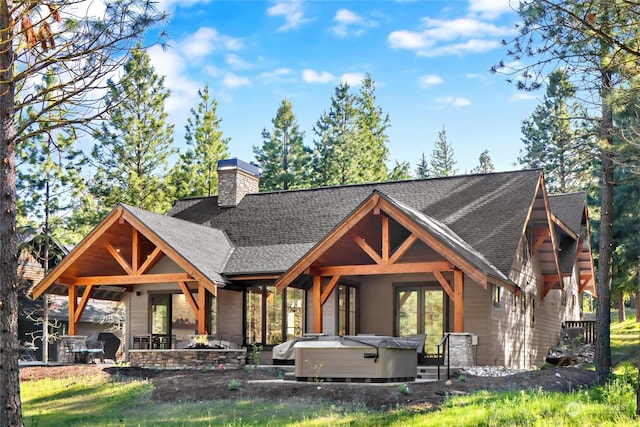 rear view of property featuring a hot tub and a patio