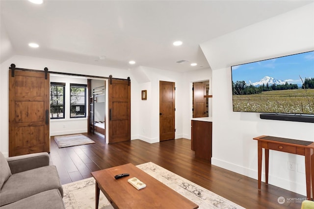 unfurnished living room with a barn door, dark hardwood / wood-style flooring, and vaulted ceiling