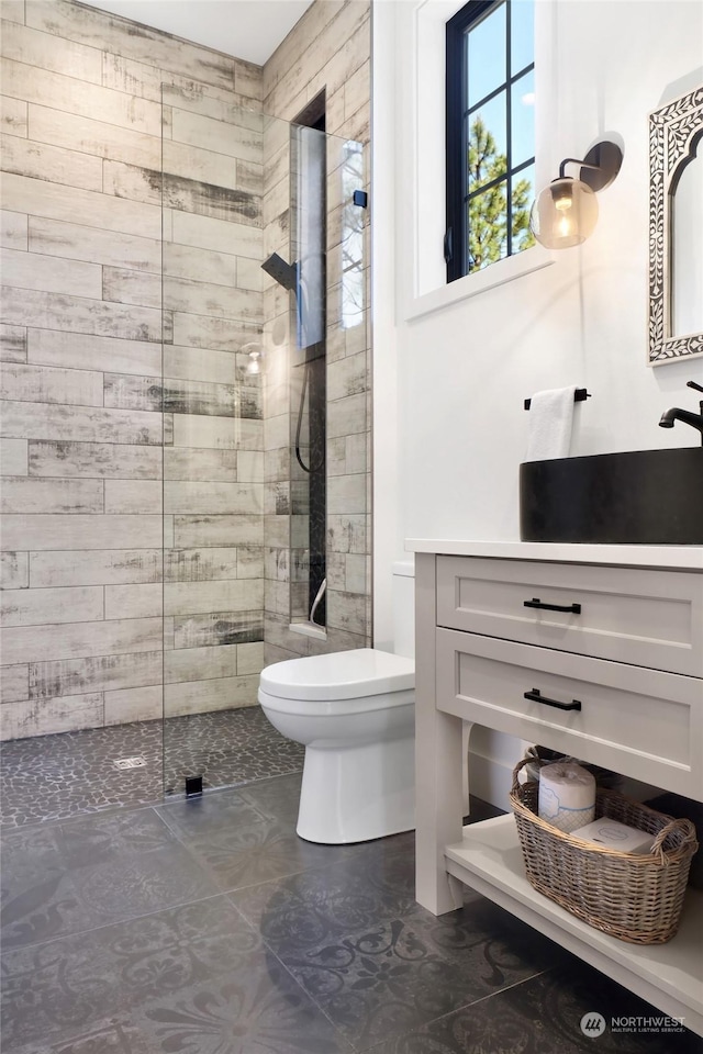 bathroom with vanity, toilet, and tiled shower