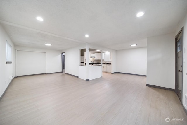 unfurnished living room featuring a textured ceiling and light wood-type flooring