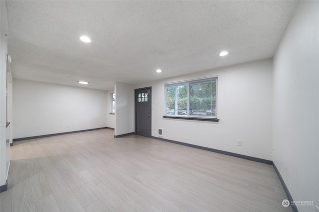 unfurnished room featuring a textured ceiling and light wood-type flooring