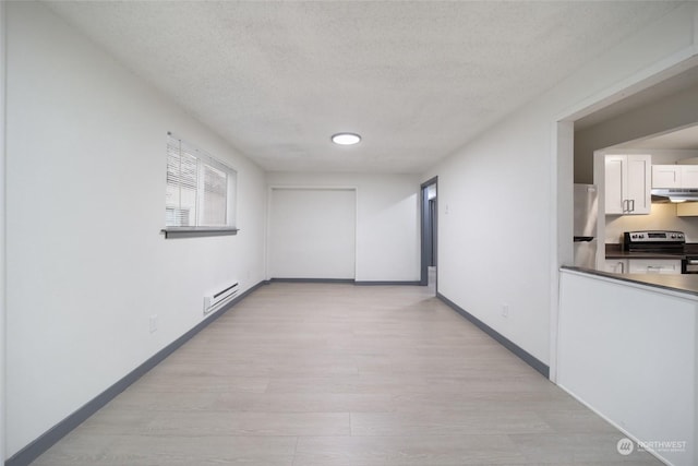 hallway with baseboard heating, a textured ceiling, and light hardwood / wood-style floors