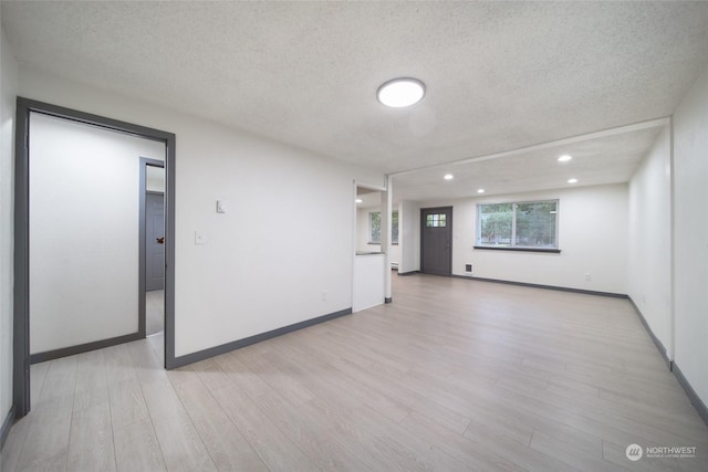 unfurnished room featuring a textured ceiling and light wood-type flooring