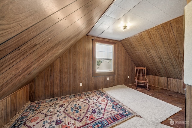 additional living space with lofted ceiling, hardwood / wood-style floors, and wooden walls