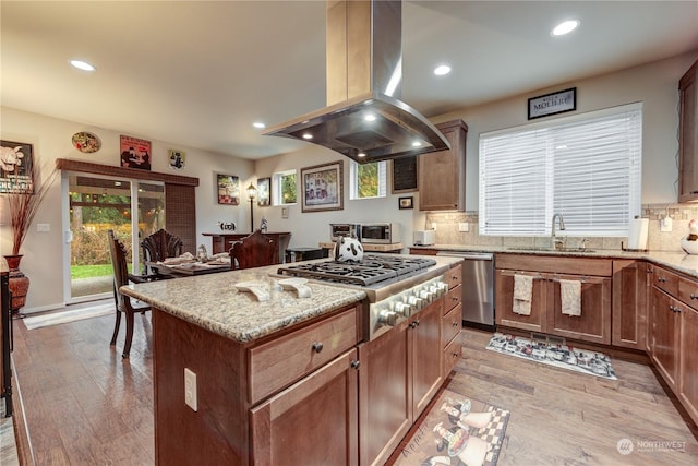 kitchen featuring sink, light hardwood / wood-style flooring, stainless steel appliances, island range hood, and a kitchen island