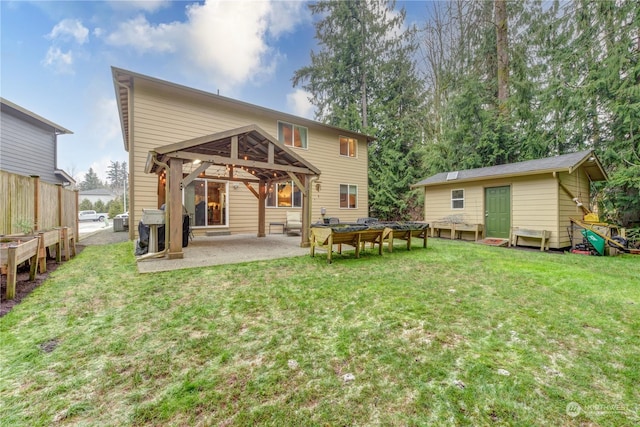 rear view of property featuring a patio, a gazebo, an outbuilding, and a lawn