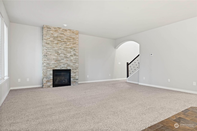 unfurnished living room with dark colored carpet and a fireplace