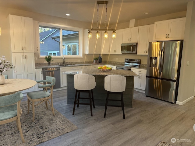 kitchen featuring hanging light fixtures, white cabinetry, appliances with stainless steel finishes, and a center island