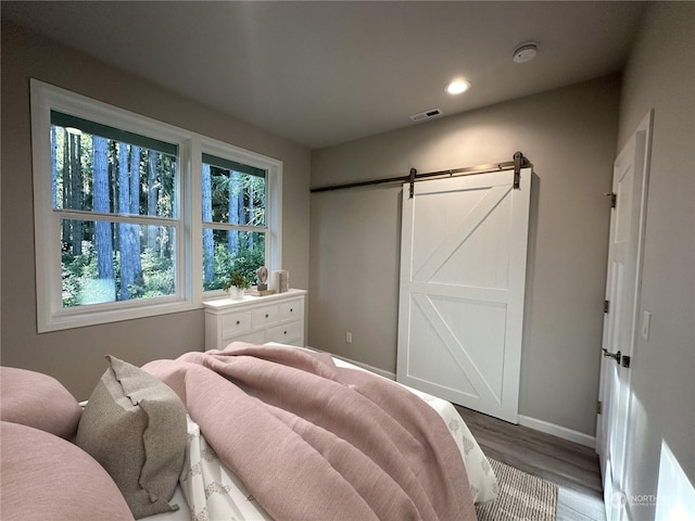 bedroom featuring a barn door and hardwood / wood-style floors