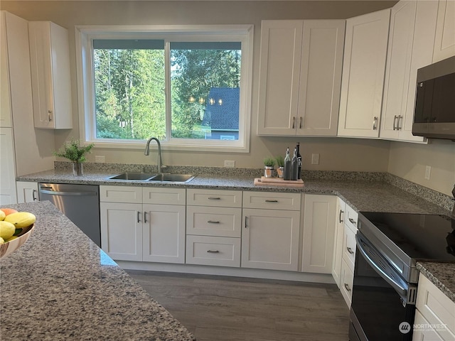 kitchen featuring dark wood-type flooring, sink, white cabinetry, stone countertops, and appliances with stainless steel finishes