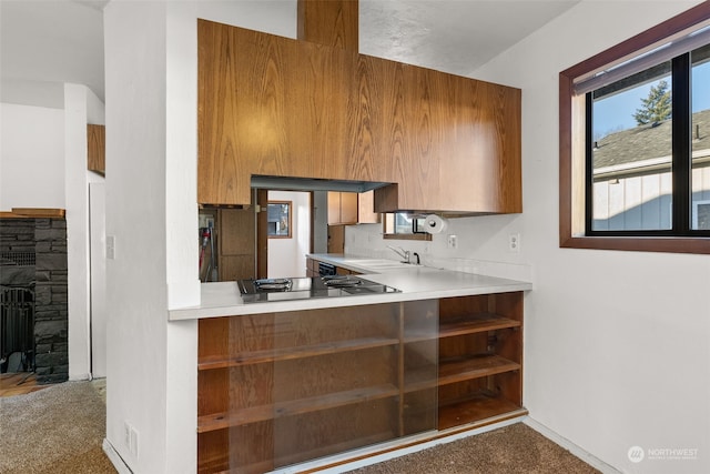 kitchen featuring carpet, sink, a stone fireplace, and black electric cooktop