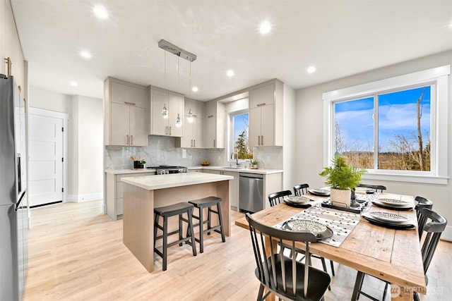 kitchen featuring hanging light fixtures, gray cabinets, stainless steel appliances, and light countertops