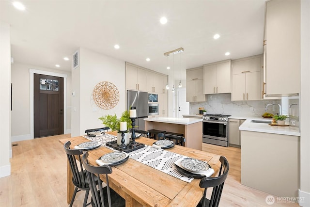 kitchen with a center island, pendant lighting, stainless steel appliances, light countertops, and a sink