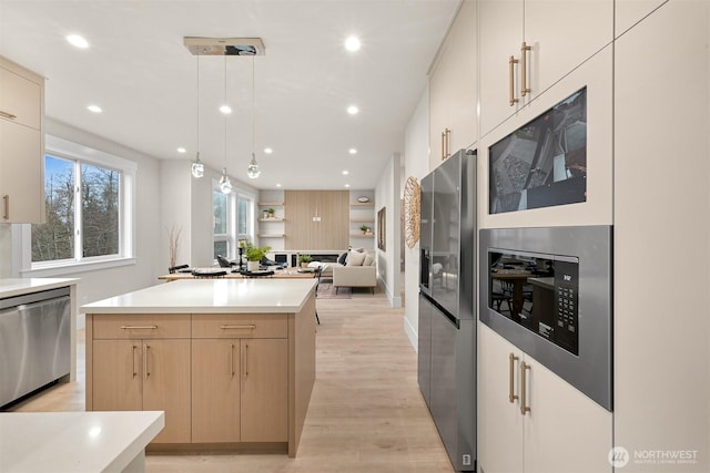 kitchen featuring open floor plan, light countertops, hanging light fixtures, appliances with stainless steel finishes, and a center island