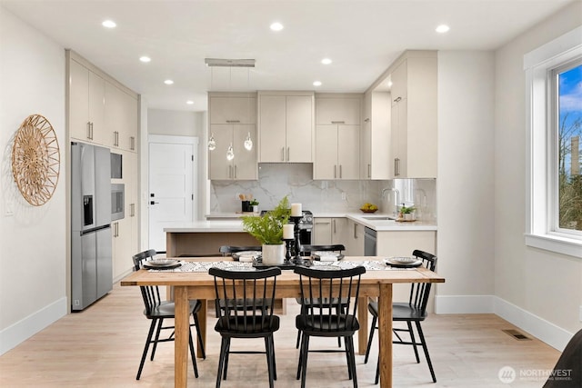 kitchen with visible vents, appliances with stainless steel finishes, light countertops, light wood-type flooring, and backsplash