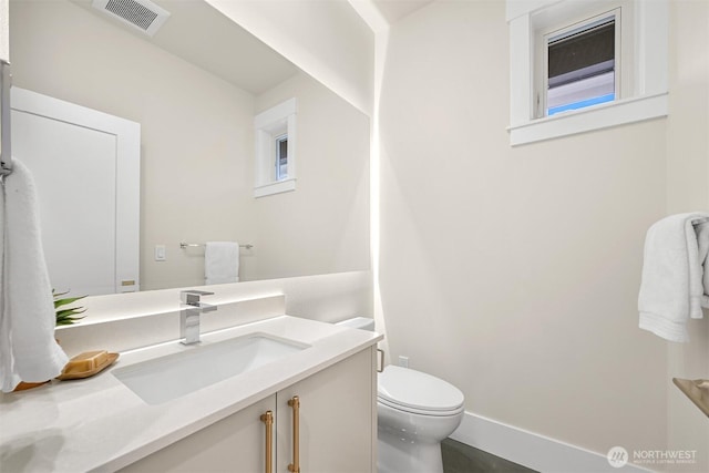 bathroom with toilet, baseboards, visible vents, and vanity