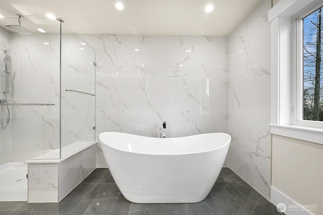 full bath with stone wall, a marble finish shower, and a freestanding bath