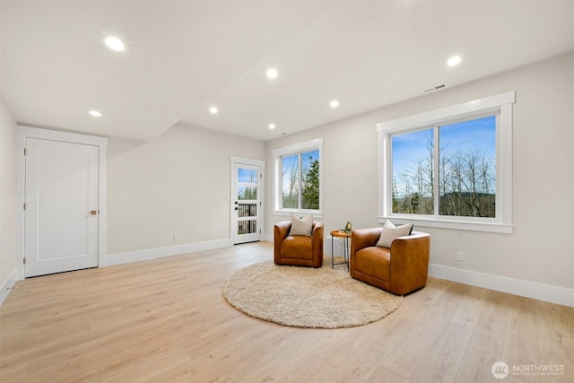 living area with light wood finished floors, recessed lighting, visible vents, and baseboards