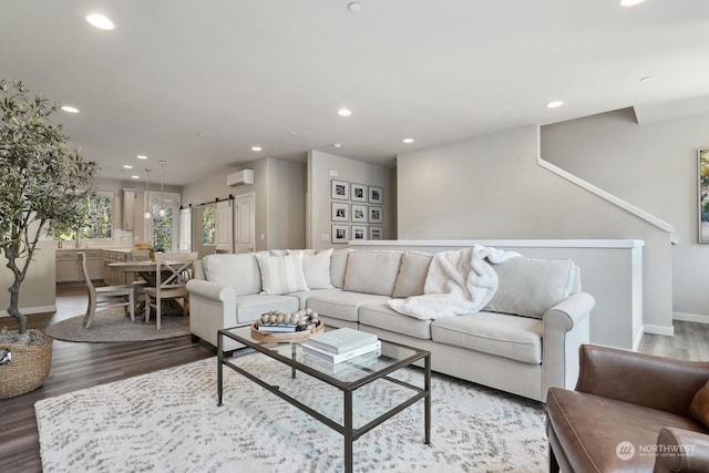 living room featuring hardwood / wood-style flooring, a wall unit AC, and a barn door